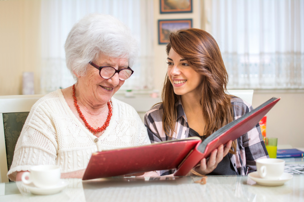 a senior woman and a young woman looking at a photo album