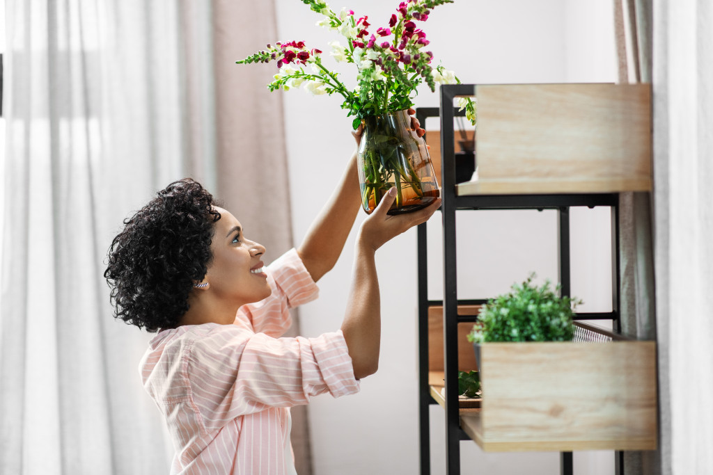 A woman placing plants and flowers in a shelf