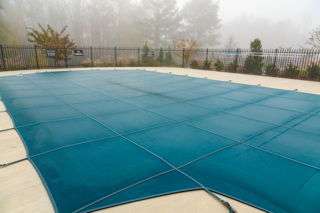 A swimming pool with a pool cover on a foggy day